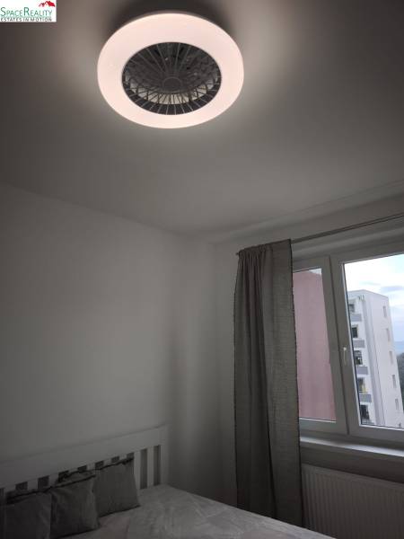 A bedroom in a 2-room apartment with modern lighting and a window with a view.