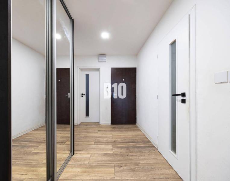 Entrance hall of a 3-room apartment with a wooden decor floor and a built-in wardrobe.