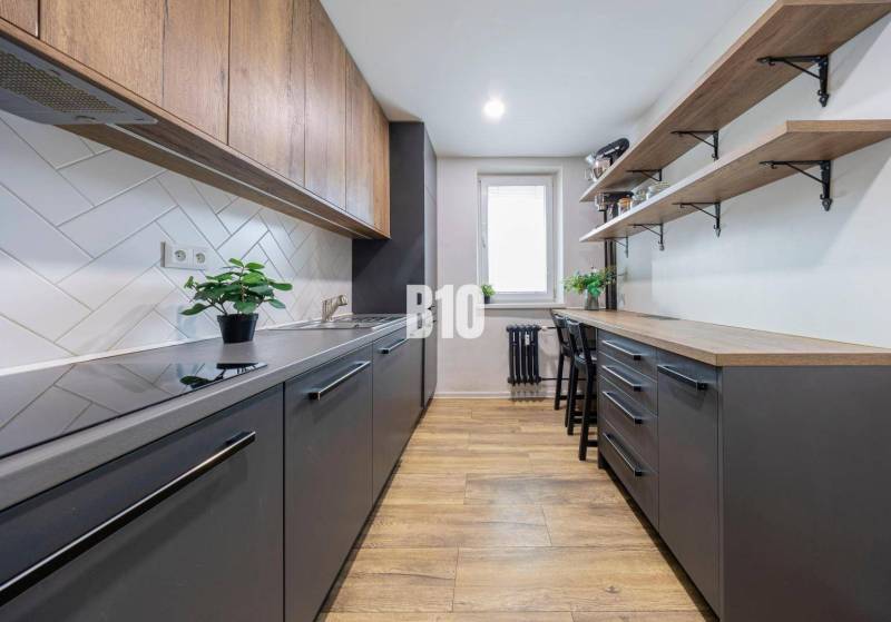 A kitchen in a 3-room apartment with a wooden decor floor and simple storage spaces.
