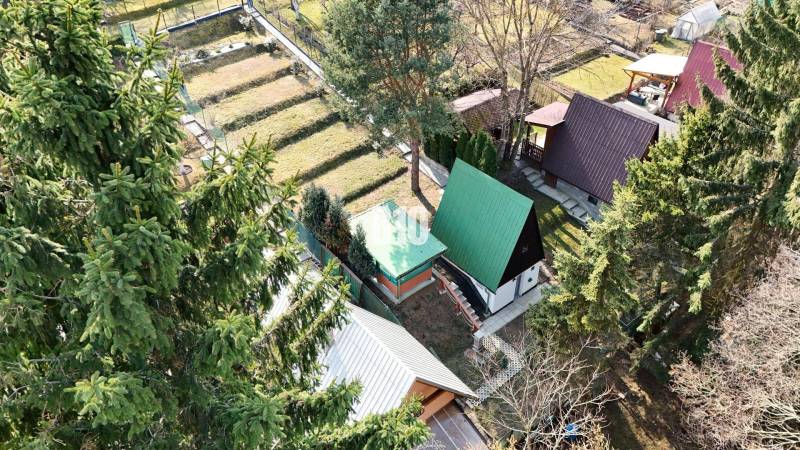 A cottage in Martin surrounded by trees, with several neighboring plots and a green roof.
