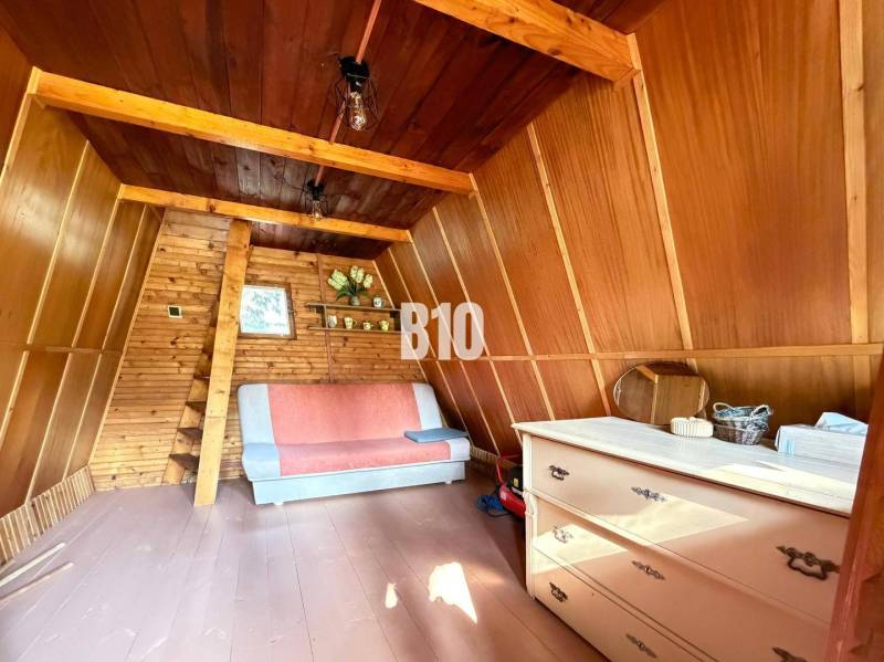 The interior of a cabin with wooden paneling and a sofa, on a floor with a wooden decor.