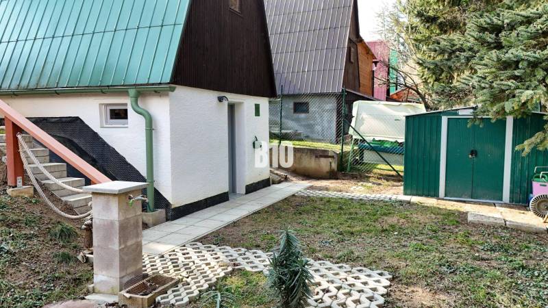 A garden with a cottage in Martin, a slide, stairs, green roofs, and a storage shed.
