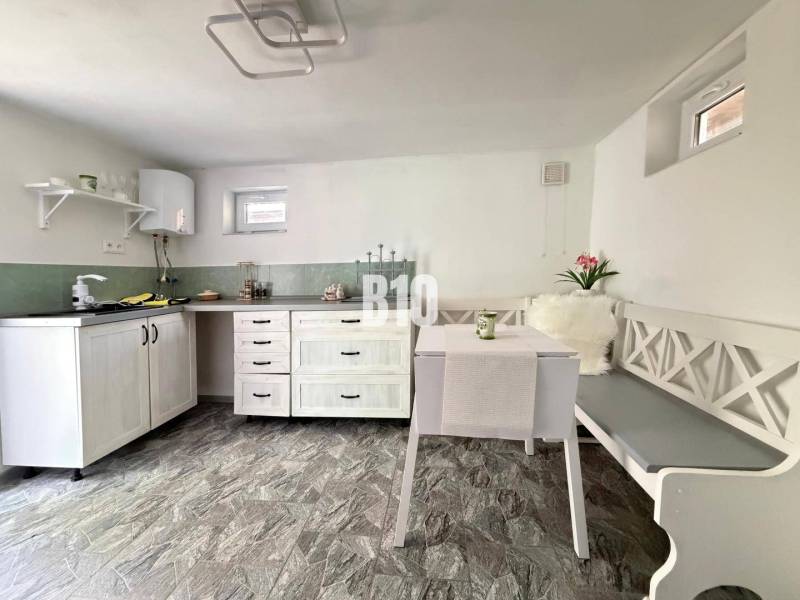 A bright cabin with a kitchenette, table, and bench, with a wooden decor floor.