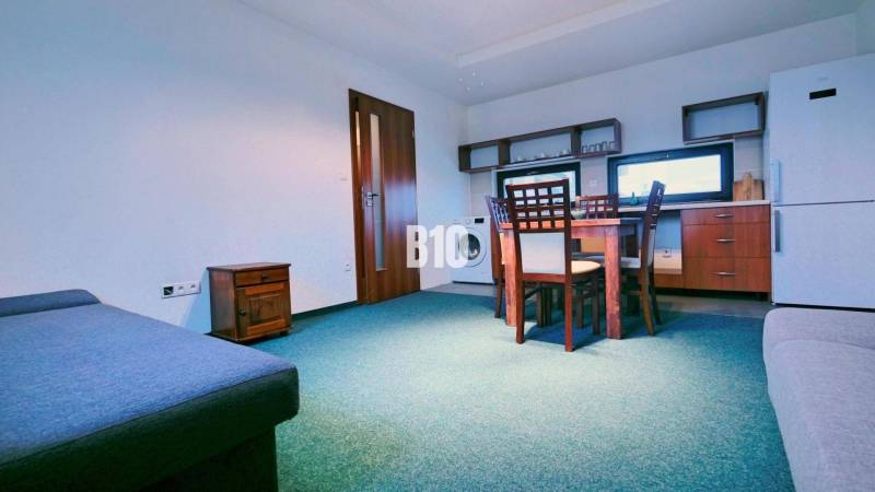 Living room with a sofa, dining table, and kitchenette in a three-room apartment.