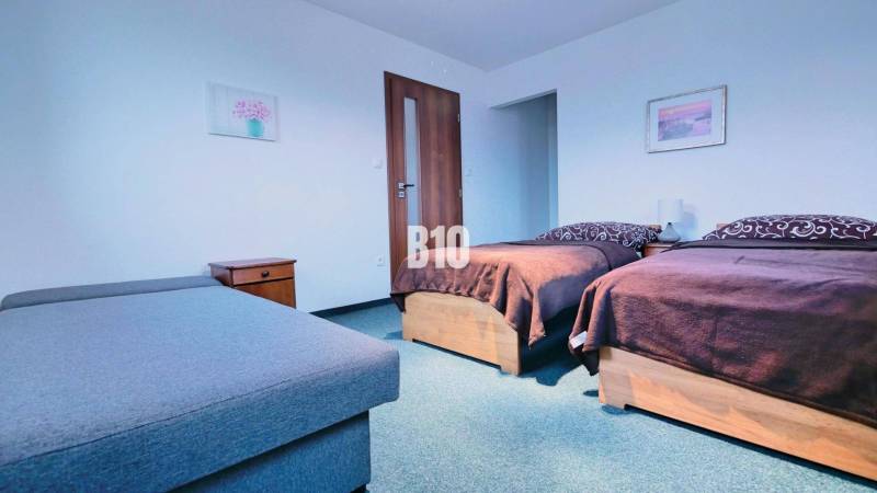 Bedroom in a 3-room apartment with two beds, nightstands, and a sofa.