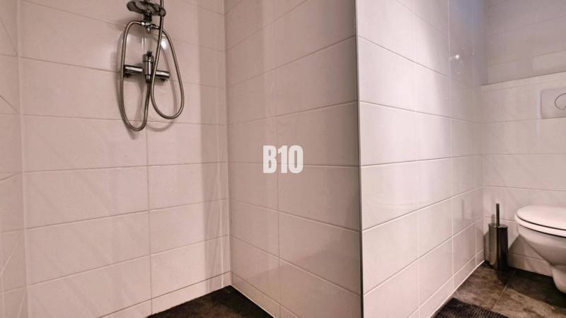 Bathroom in a 3-room apartment with white tiles, a shower, and a toilet.