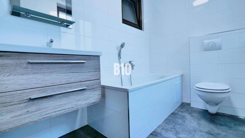 Bathroom in a 3-room apartment with a bathtub, sink, toilet, and floor with a wooden decor.