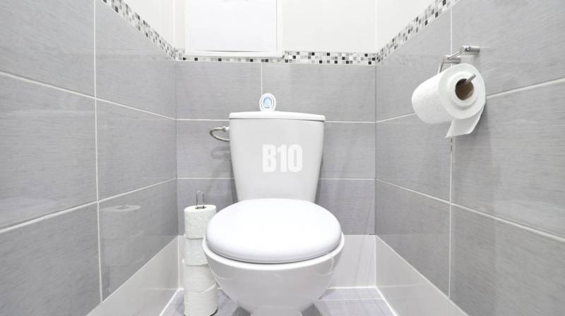 A bathroom in a 2-room apartment with a toilet, tiled with gray tiles.