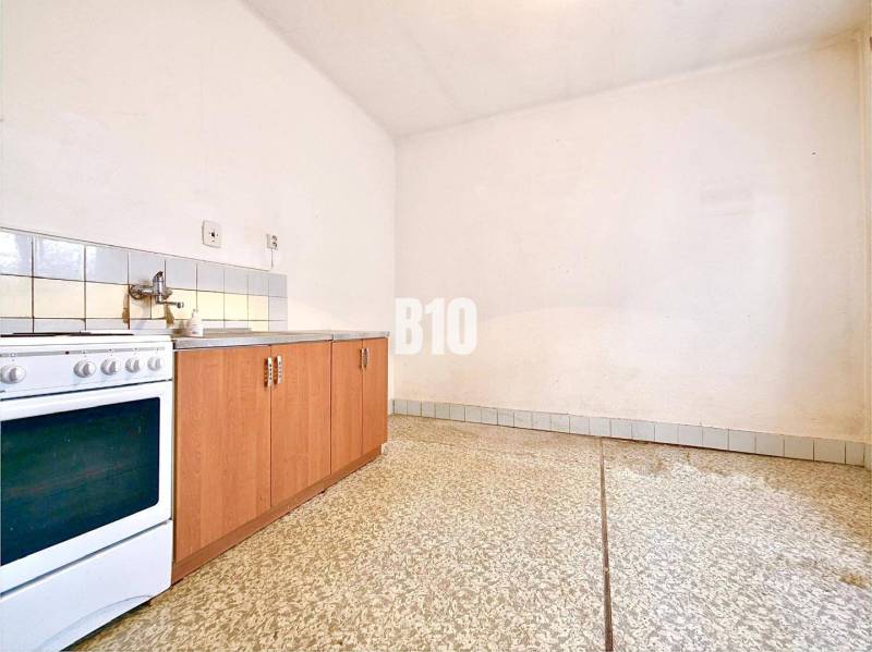 A kitchen in a family house with a kitchen unit, a stove, and a tiled floor.