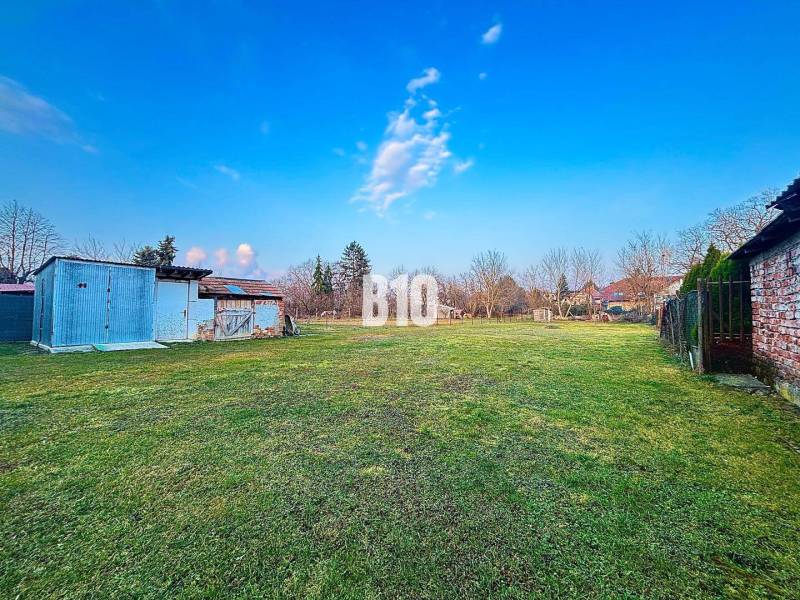 A plot of land near a family house in Sľažany with metal structures and a grassy area.