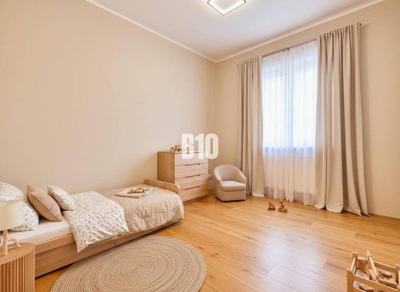 Children's room with a bed, armchair, and dresser, with a wooden decor floor.