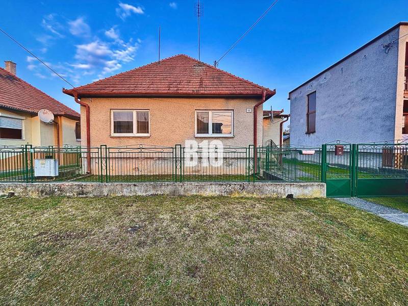 A family house in Sľažany with a front garden and a sloped roof between neighboring buildings.