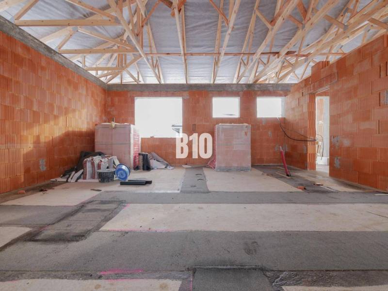 Construction of a family house with an unfinished wall and a wooden ceiling.