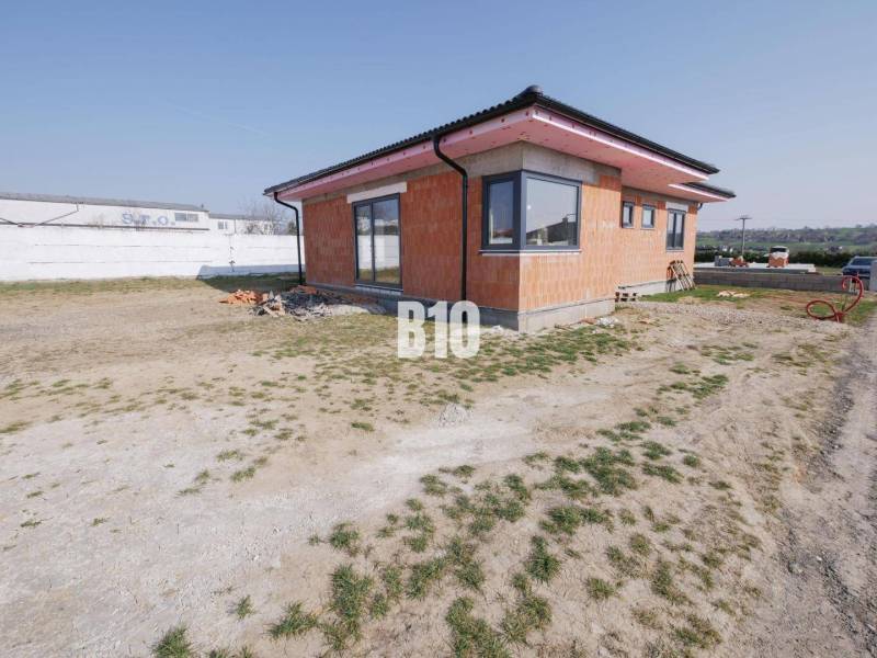 A family house in Veľký Lapáš with an unfinished facade, surrounded by a grassy plot.