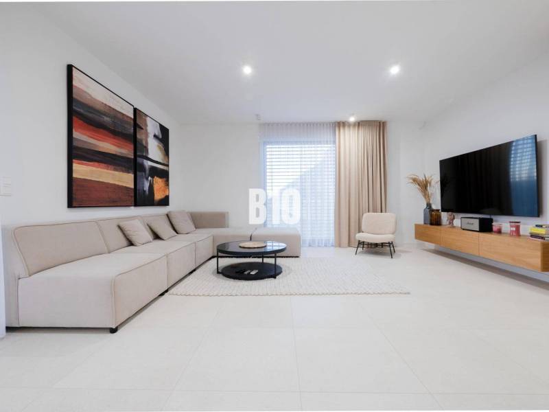 Living room with a comfortable sofa, large television, and modern art on the wall.