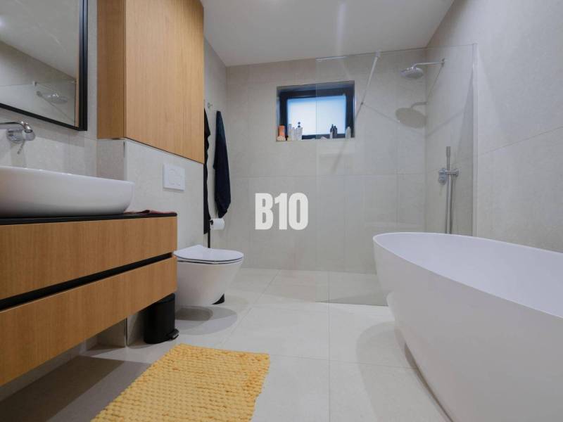 A bathroom in a family house with a bathtub, toilet, and sink, with light tiles.