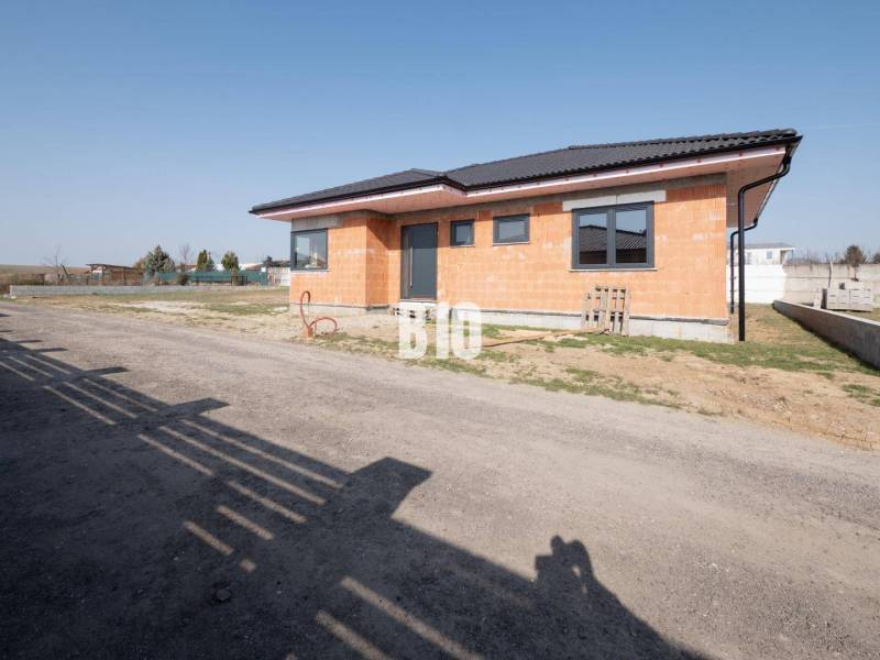 A family house under construction in Veľký Lapáš with a simple facade on an unkempt plot.