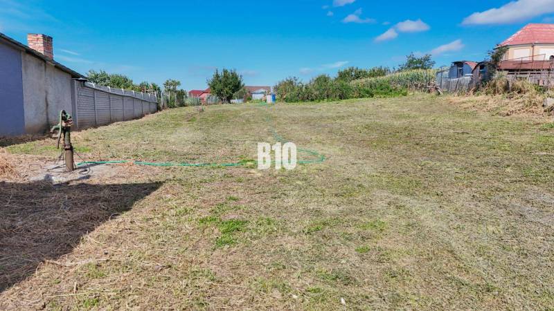 A residential plot in Rumanová with a grassy surface, next to fences and houses.