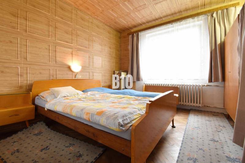 A bedroom with light from the window, wooden furniture, and a floor with a wooden decor in a 3-room apartment.