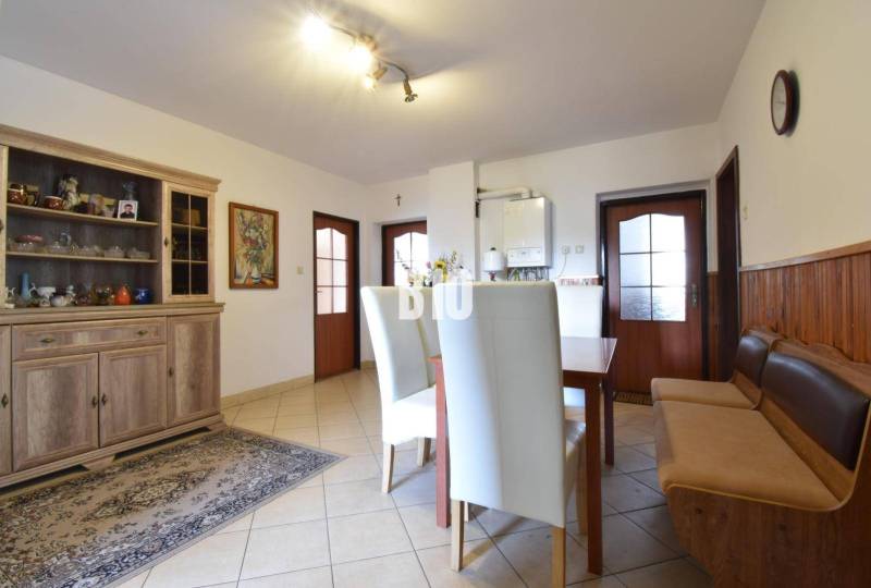 Dining area in a family house with a wooden sideboard and white chairs.