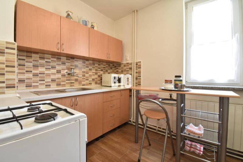 A kitchen in a family house with wooden furniture and a mosaic on the wall.