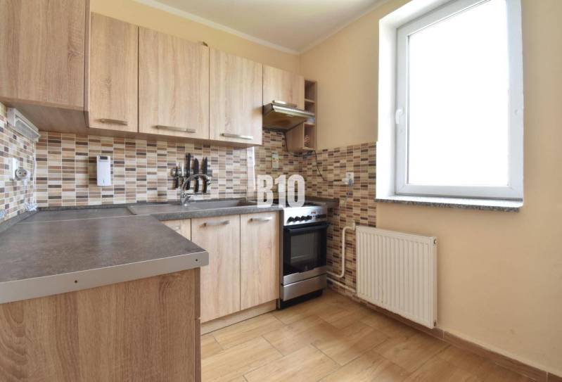 A kitchen in a family house with wooden cabinets and a tile mosaic on the wall.