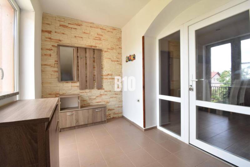 Interior of a family house with a coat rack wall and glass doors leading to the balcony.