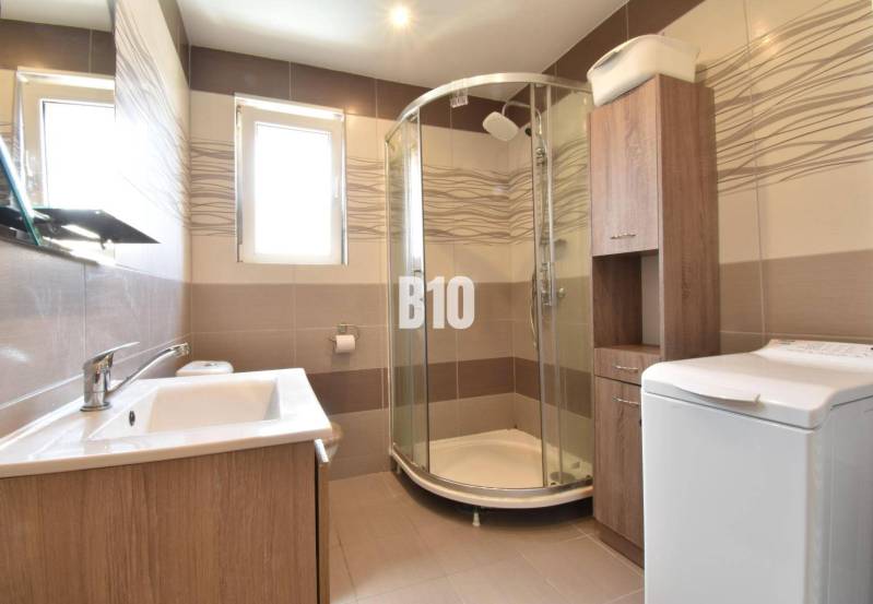 Bathroom with a sink, shower, and washing machine in a family house.