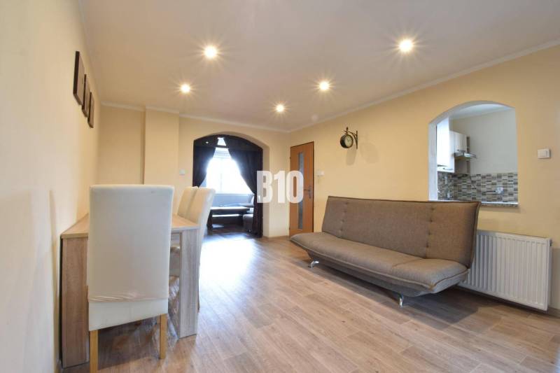 Living room with a sofa, dining table, and kitchen passage in a family house.