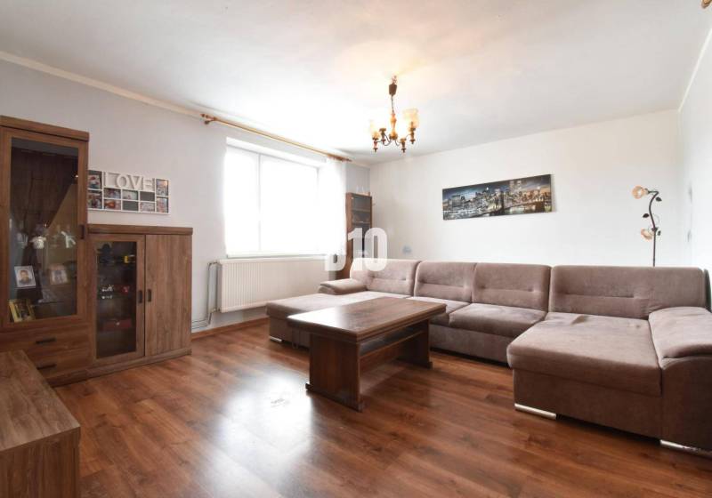 Living room in a family house with a sofa, wooden furniture, and wall decorations.