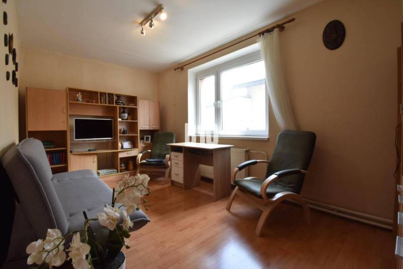 Living room with wooden furniture, a sofa, and flowers in a family house.
