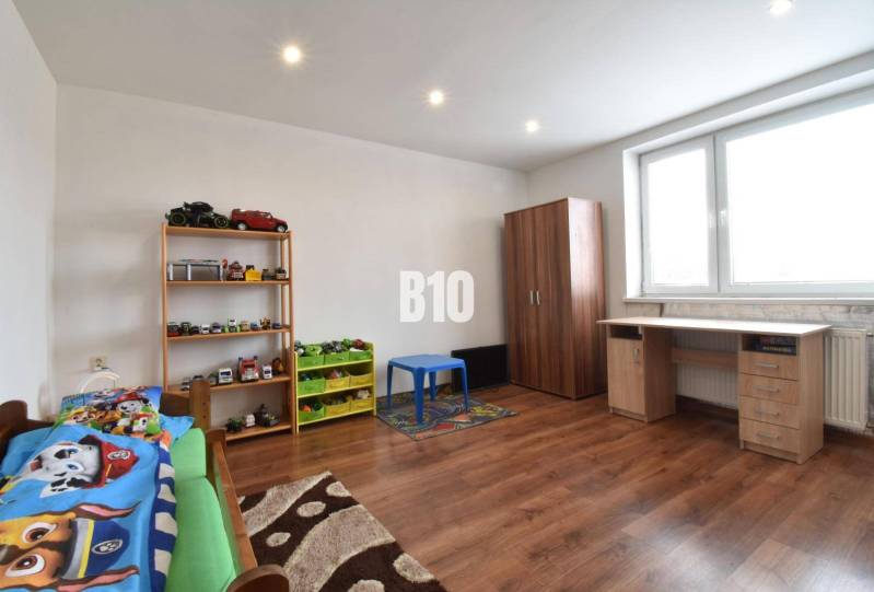Children's room in a family house with wooden flooring and toys on the shelf.