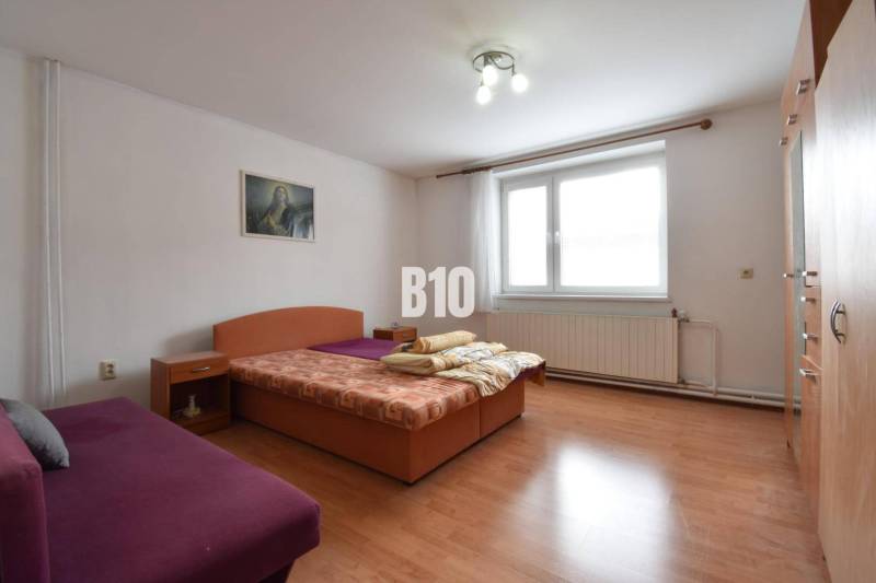 Bedroom with wooden floor, bed, and sofa in a family house.