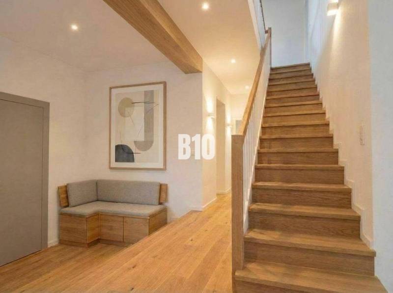 Interior of a cabin with wooden decor, stairs, bench, painting, neutral colors.