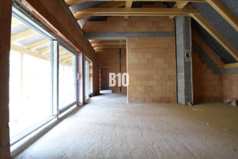 Unfinished interior of a family house with large windows and brick walls.