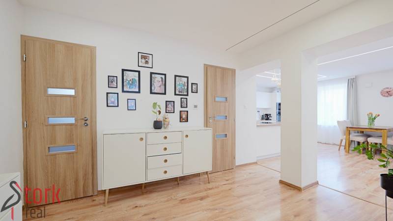 Interior of a family house with a wooden decor floor, white furniture, and decorations.