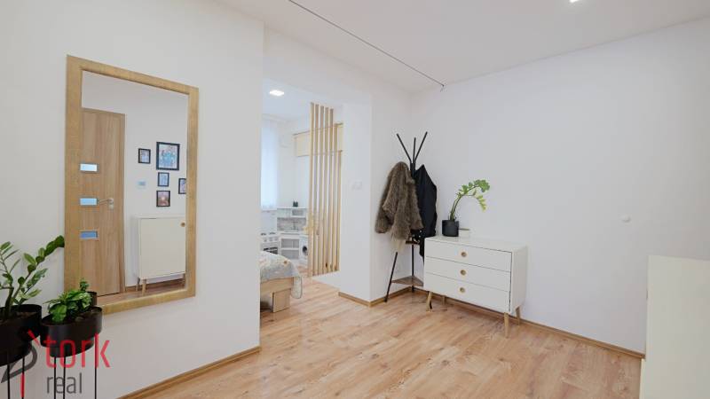 Interior of a family house with a wooden decor floor, a dresser, and a coat rack.