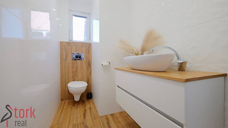 A bathroom with a sink on a dresser and a floor with a wood decor.