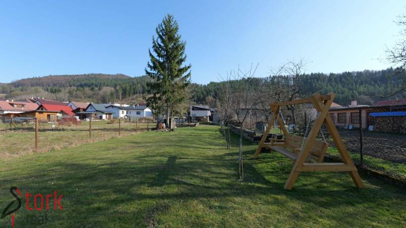 The garden of a family house on Mládeže Street in Dolný Hričov with a swing and trees.