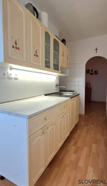A kitchen in a 2-room apartment with a wooden decor floor and an arched transition.