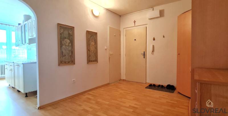 Entrance hall with wood-patterned flooring for a 2-room apartment, kitchen in the background.