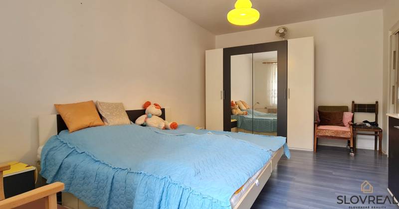 Bedroom in a 2-room apartment with a bed, wardrobe, and wooden decor flooring.