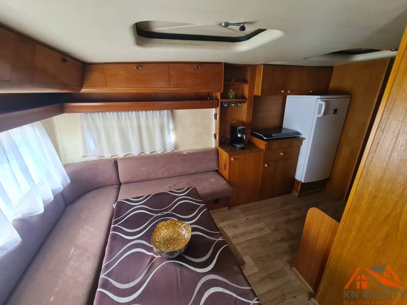 Interior of a cabin with a wood-patterned floor, a sofa, and a kitchenette.