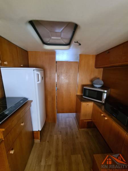 Interior of a cabin with wood-patterned flooring, a microwave, and a refrigerator.