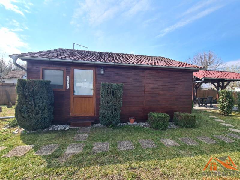 A wooden cottage in Štúrovo with a red tile roof and a stone pathway.