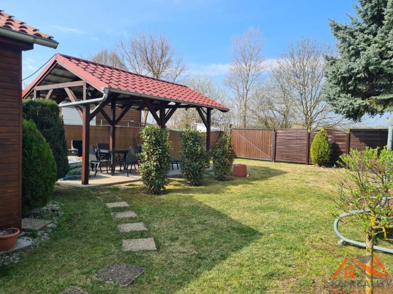 A cottage in Štúrovo with a gazebo, lawn, and trees; a peaceful garden for relaxation.