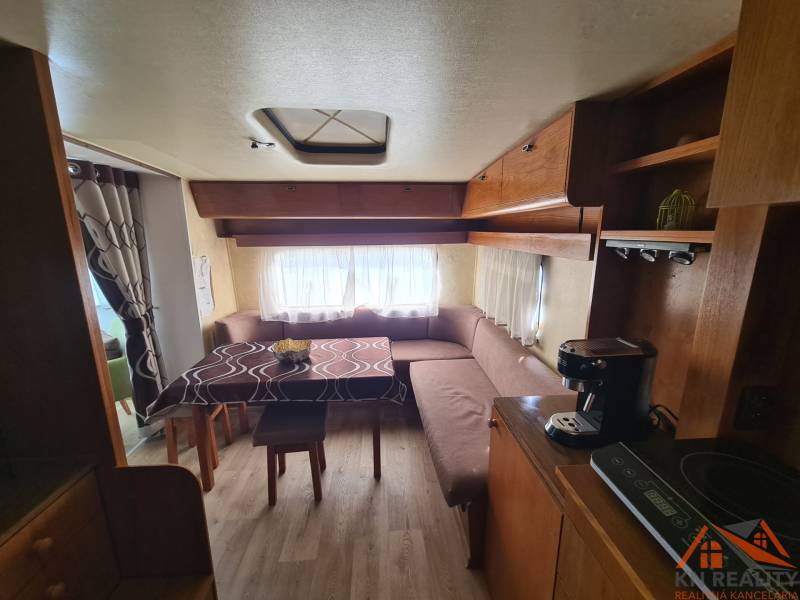Interior of a cabin with a sofa, table, and wooden decor flooring.