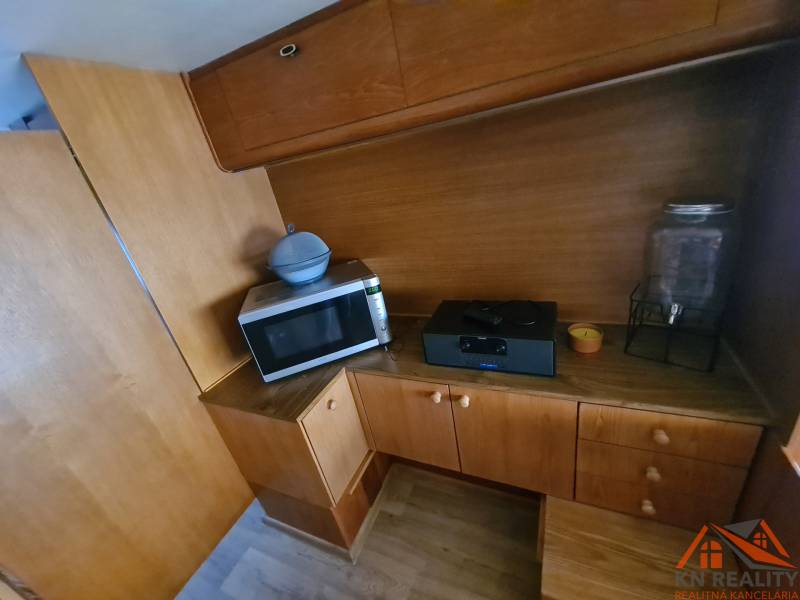 Cottage kitchen corner with wooden decor, microwave, and glass container.