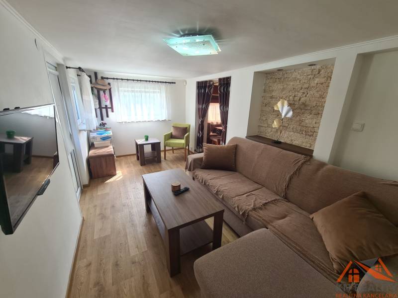 Living room with wood-patterned flooring, comfortable sofa, and television in a cabin.