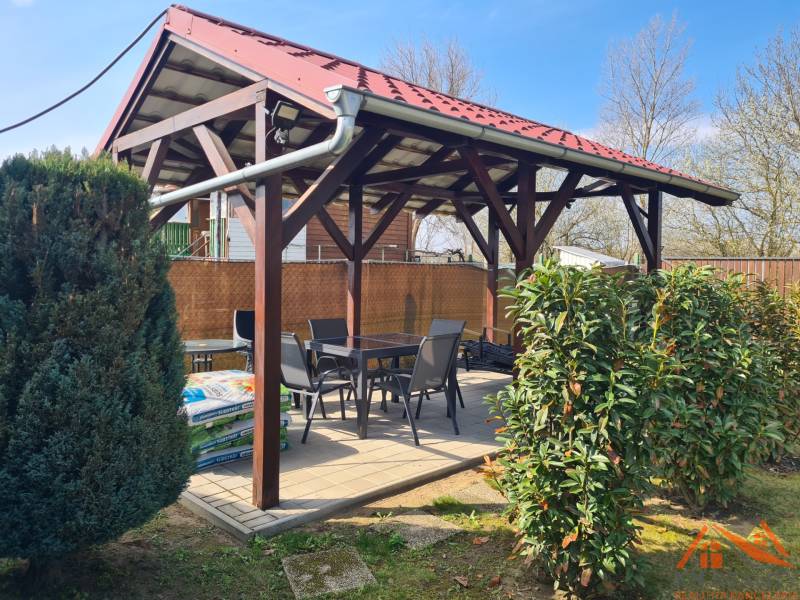 A covered terrace at the cottage in Štúrovo, surrounded by greenery and comfortable seating.